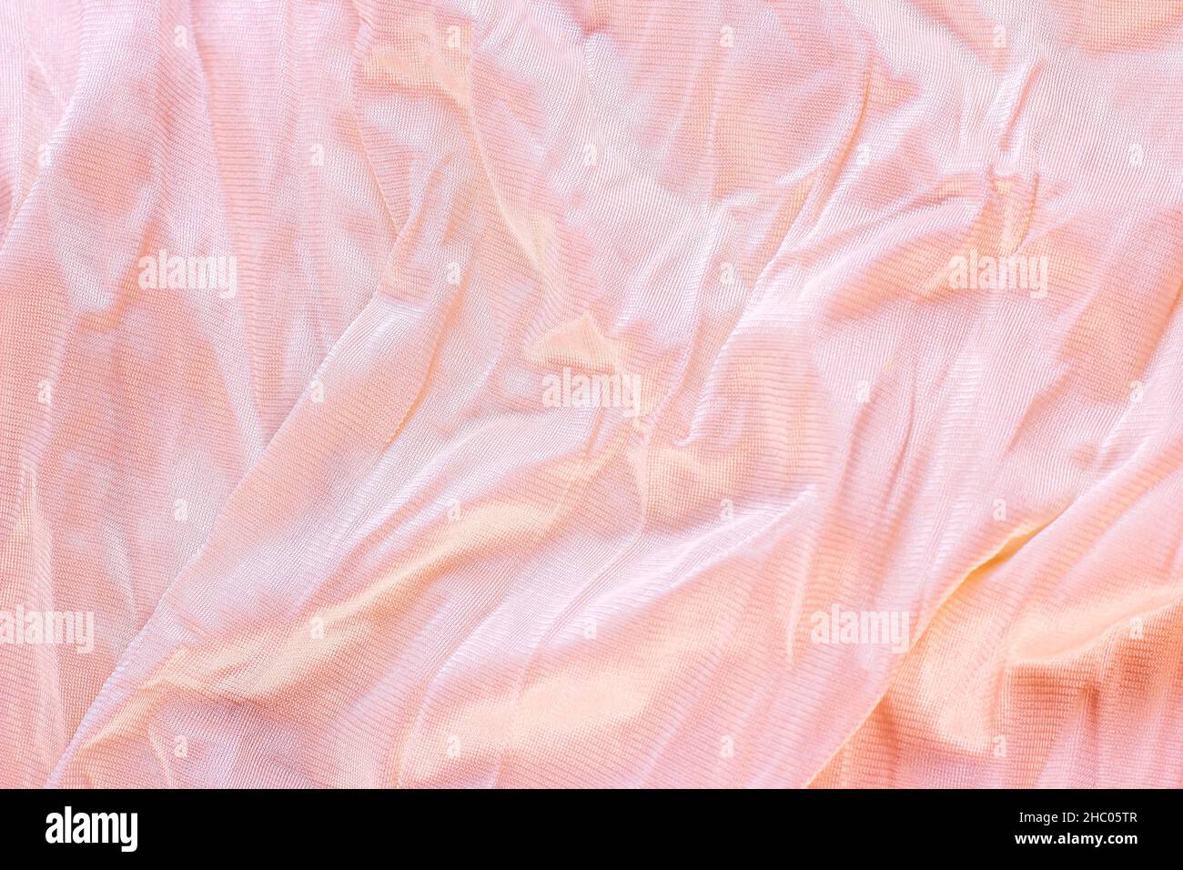 Colore rosa pastello chiaro nylon ondulato e motivo in poliammide come sfondo liscio testurizzato. Tendaggi in tessuto morbido di colore rosa pallido. Foto Stock