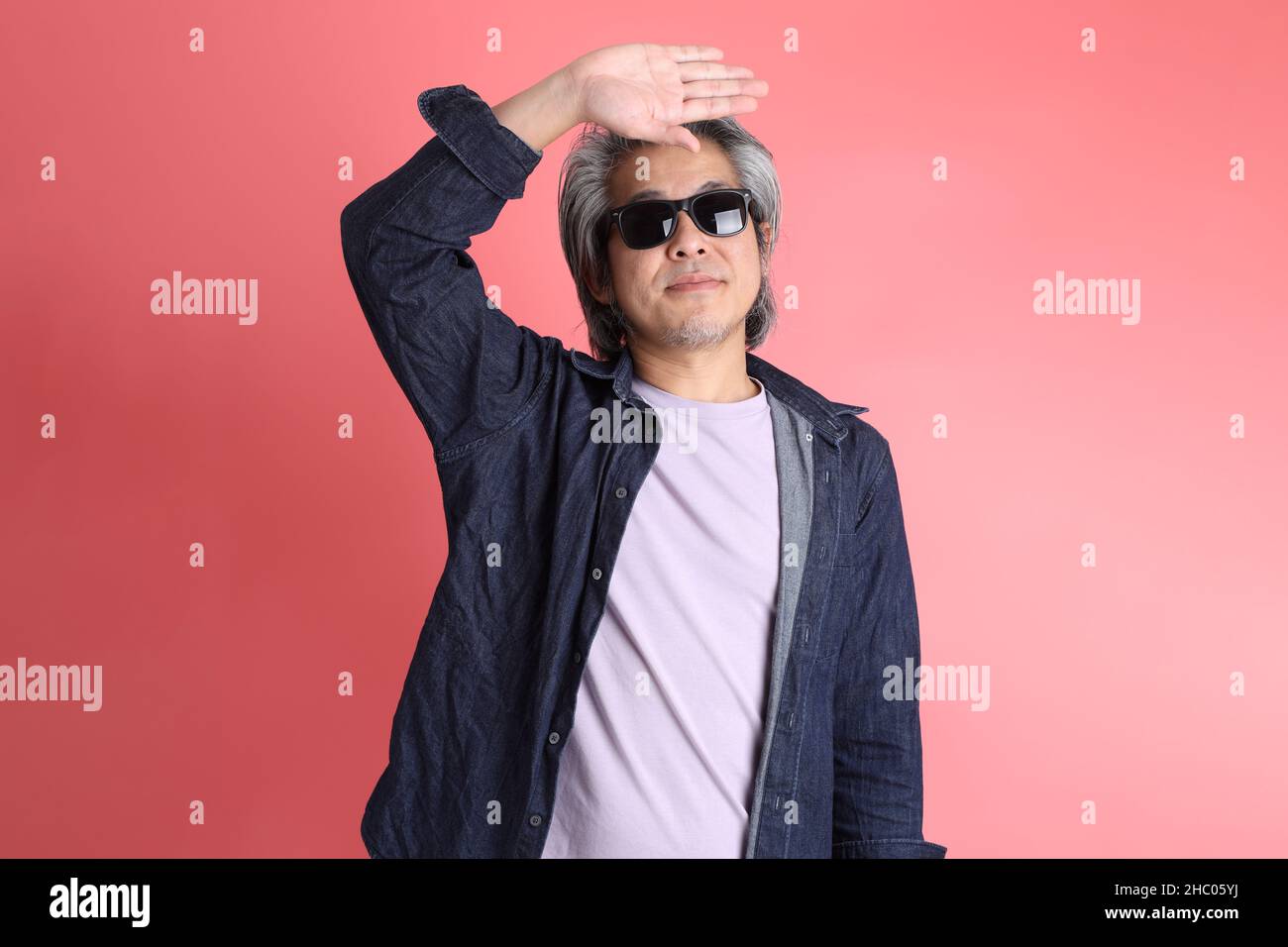 L'uomo asiatico in piedi su sfondo rosa. Foto Stock