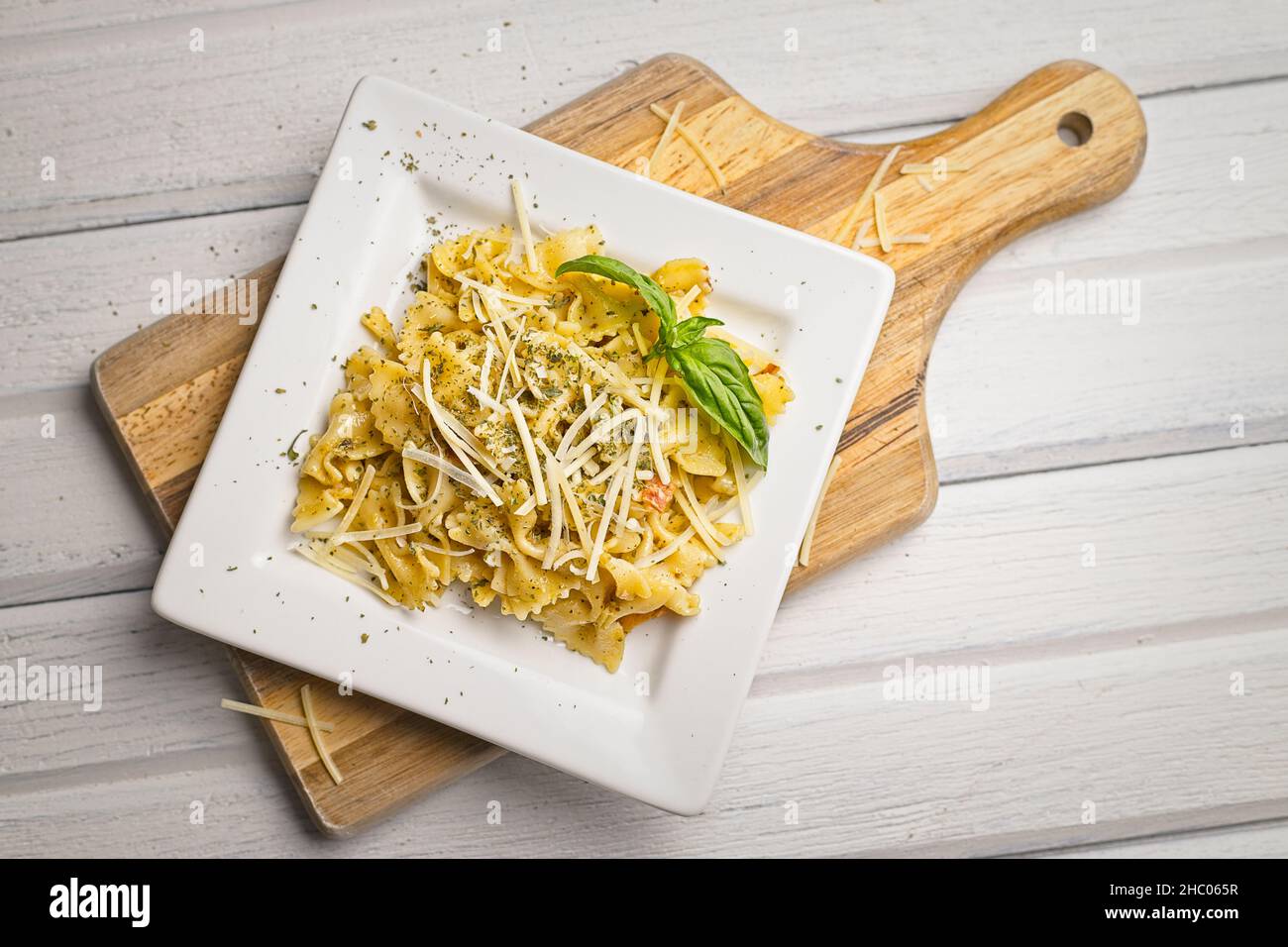 Panoramica di un piatto di pasta bowtie condito con parmigiano e una guarnitura al basilico. Foto Stock