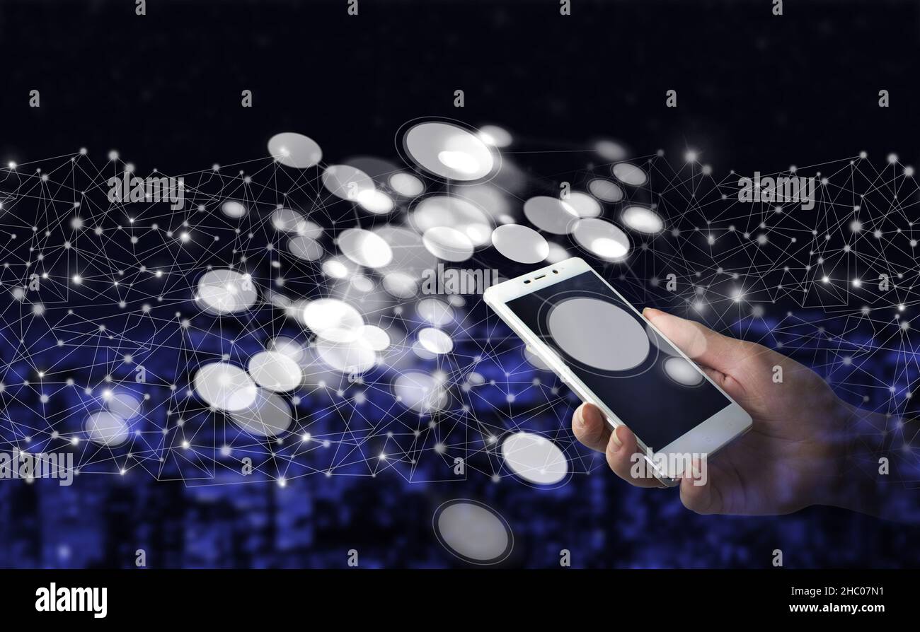 Smartphone bianco portatile con ologramma a diagramma circolare digitale su sfondo sfocato scuro della città. Connessione di rete innovativa e globale, DAT Foto Stock