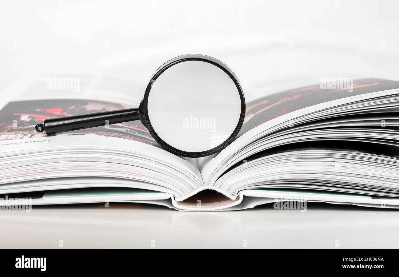 Lente di ingrandimento su carta aperta libro d'arte con pagine. Concetto di ricerca accademica. Foto Stock