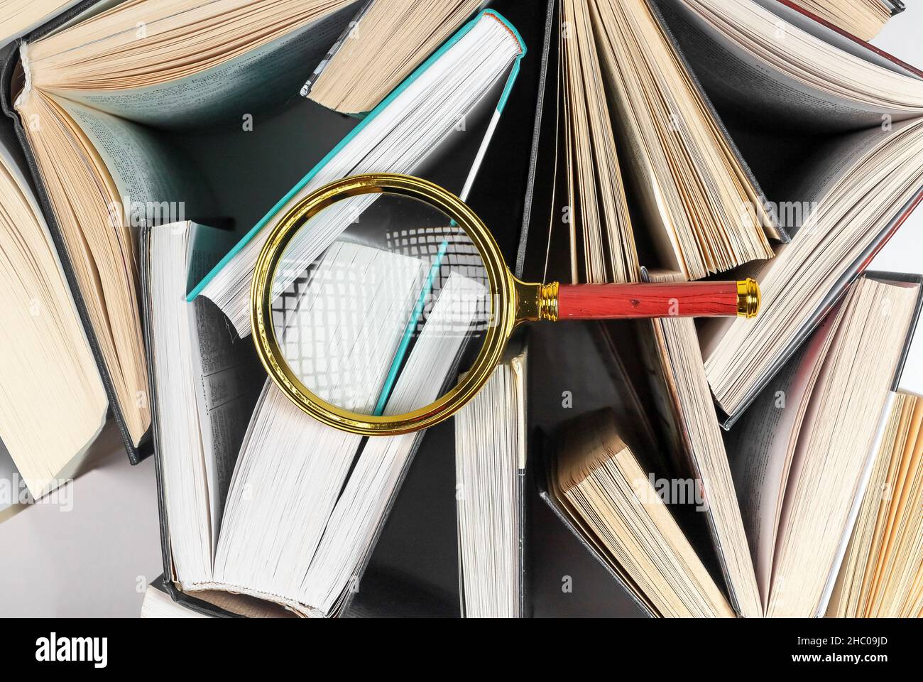 Lente di ingrandimento su libri diversi. Concetto di focalizzazione sulla conoscenza, la lettura e la ricerca. Foto Stock