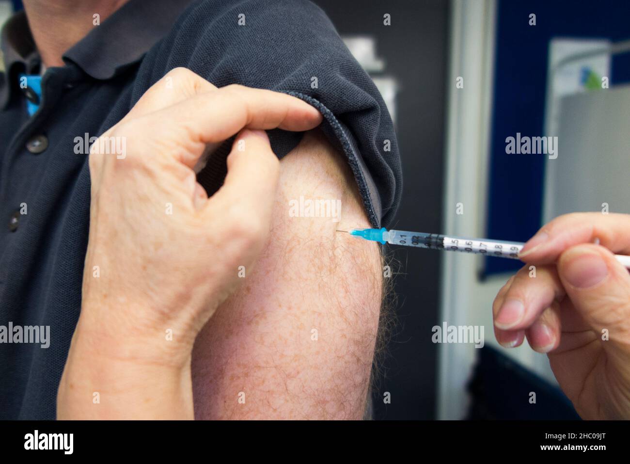 L'infermiere di pratica da un ambulatorio di GP sta somministrando l'iniezione di richiamo del vaccino di BioNTech, Pfizer ad un uomo per proteggere contro l'infezione di COVID-19, durante una clinica di vaccinazione. (127) Foto Stock