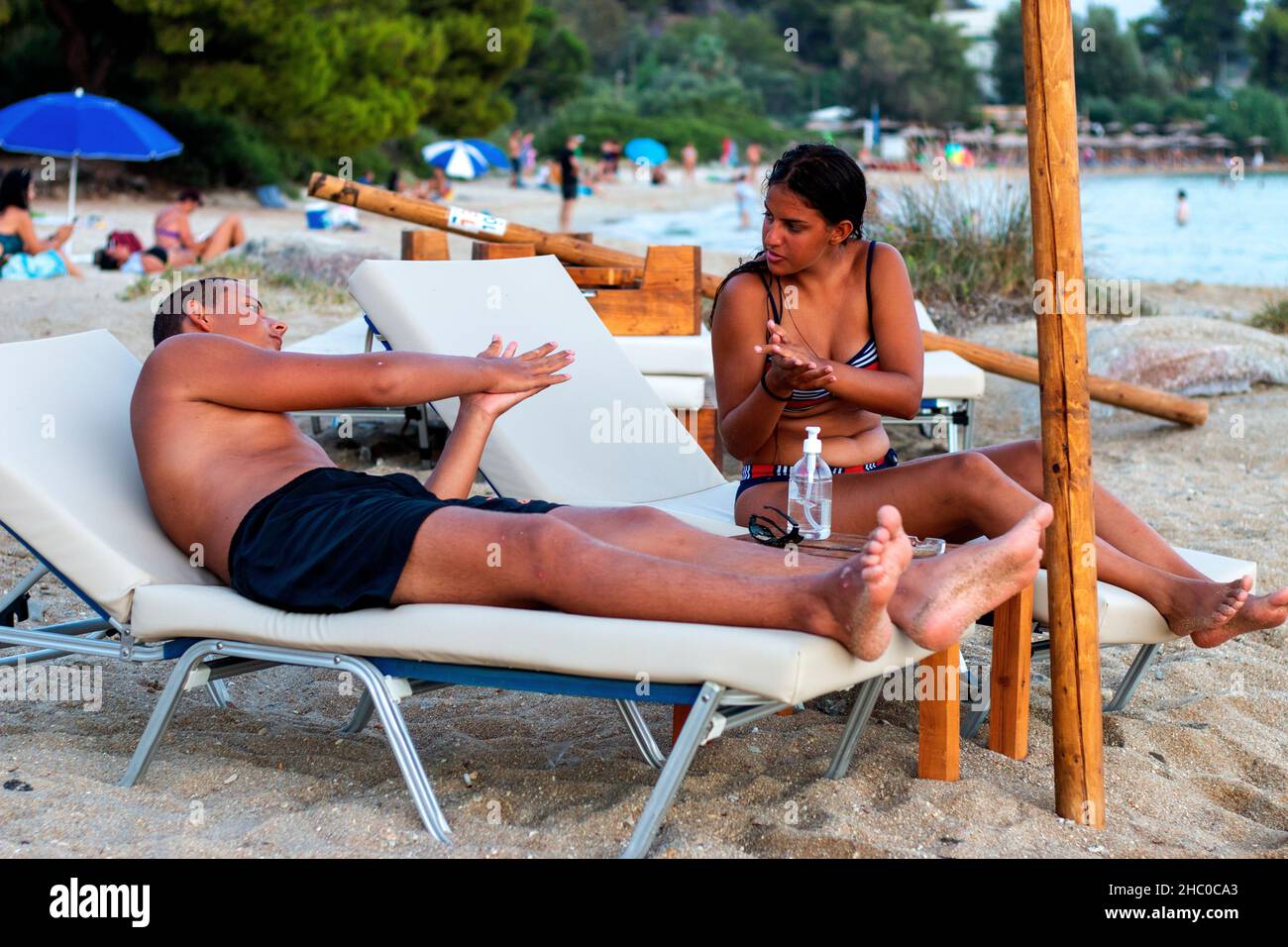 Una coppia innamorata seduta al lettino solare in spiaggia Foto Stock