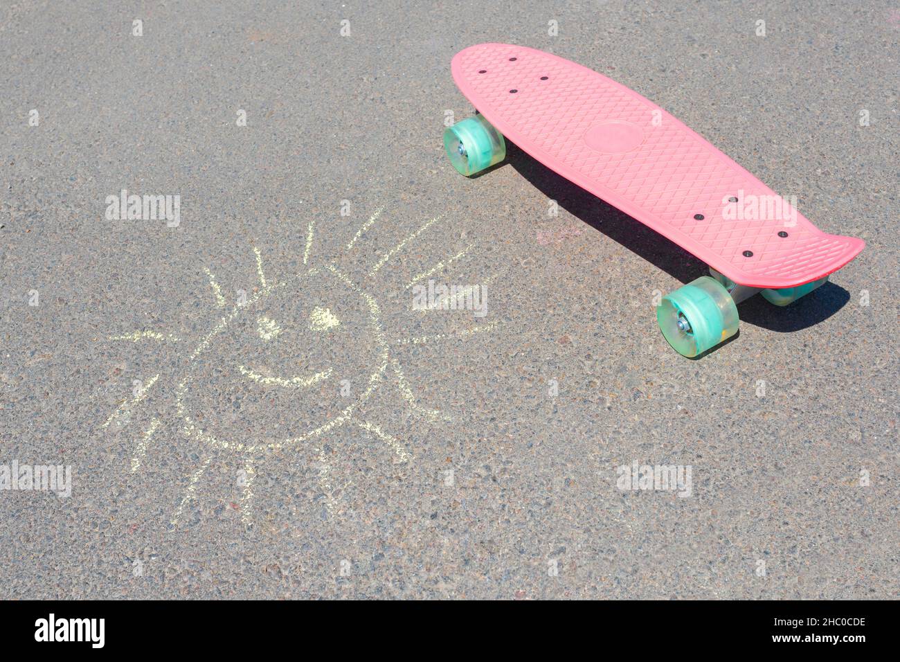 Disegnare il sole su asfalto e skateboard da vicino. Foto Stock