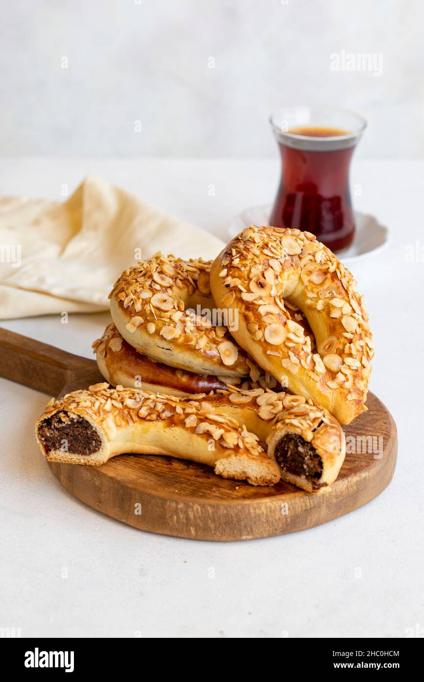 Ay coregi turco e tè. Biscotti alla luna su sfondo bianco. Croissant con cioccolato al cacao e uva passa. Primo piano. Messa a fuoco selettiva. Vista verticale. Storia Foto Stock