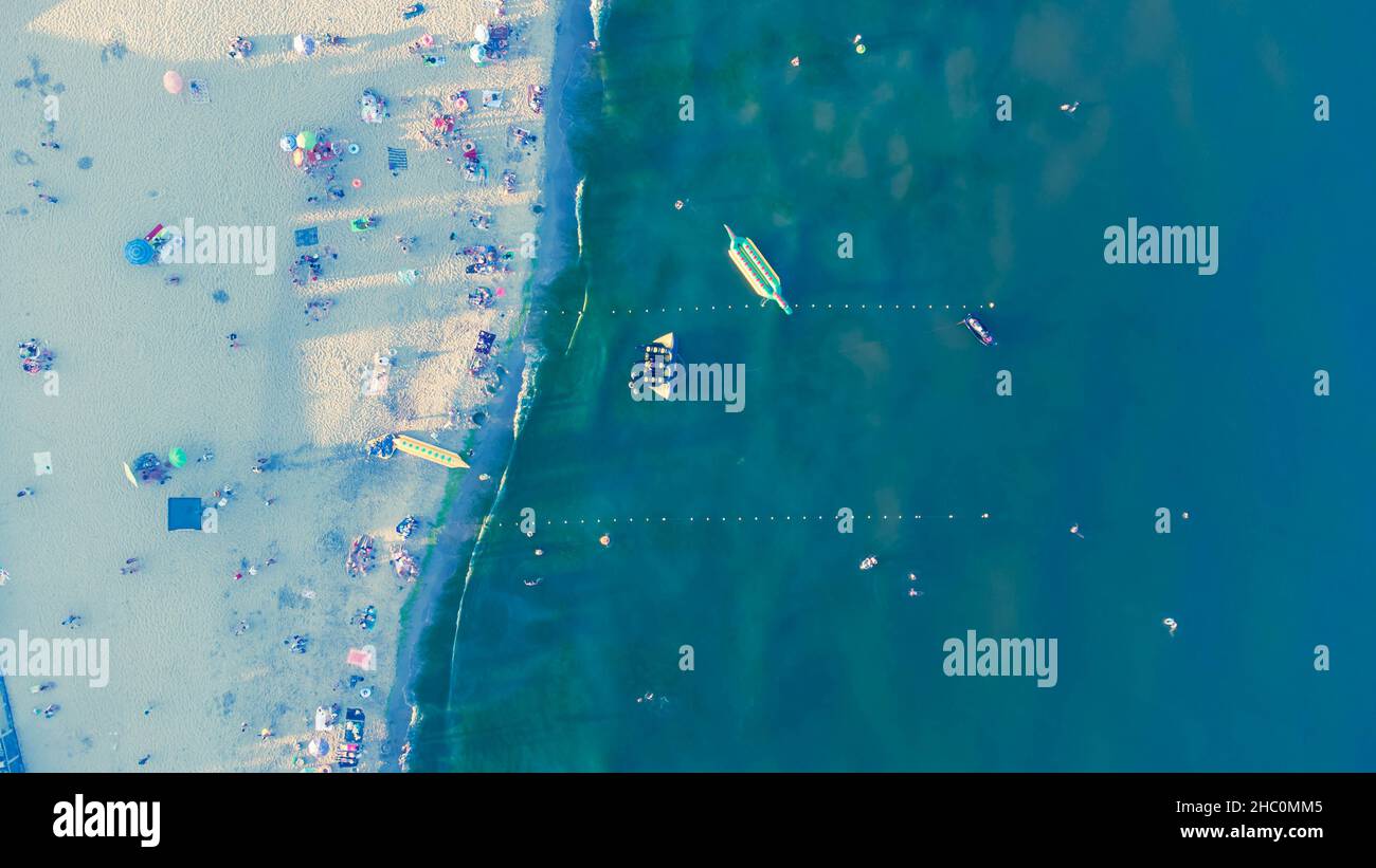 Spiaggia di sabbia con gente che riposa all'alba in estate. Vista aerea. Vista dall'alto della costa marina. Foto Stock