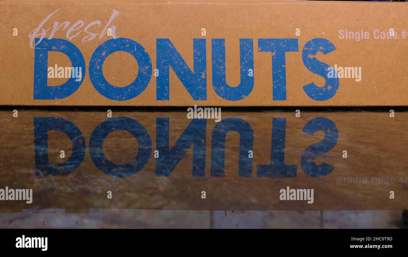 Scatola di cartone di ciambella con le parole Donuts freschi e riflessione sul piano di banco della cucina di marmo. Foto Stock