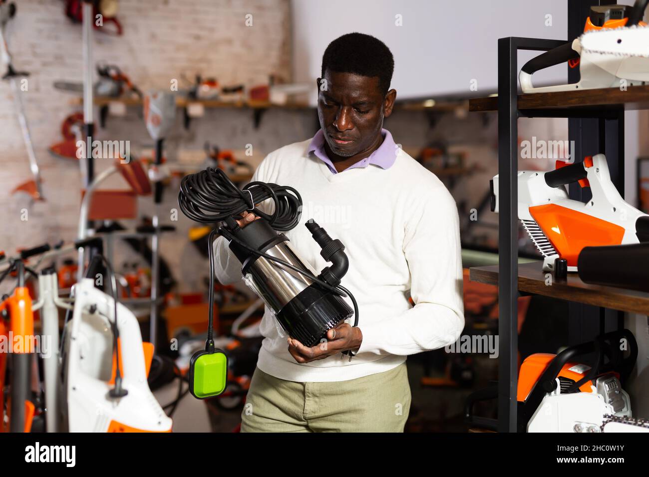 Uomo che decide sulla pompa sommergibile migliore nel negozio di attrezzatura da giardino Foto Stock