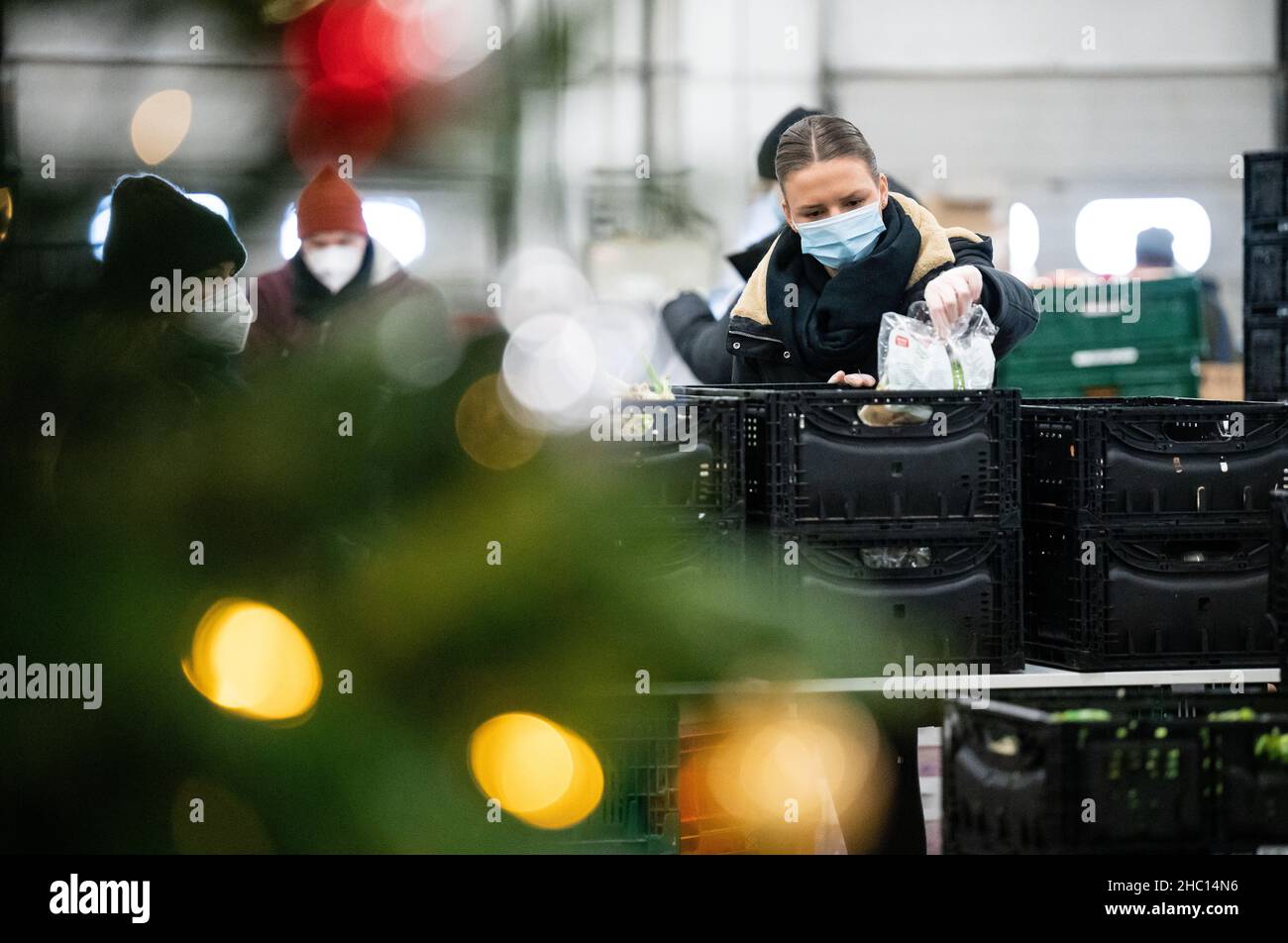 22 dicembre 2021, Berlino: Celina Räder mette il cibo in sacchi di carta in una sala del Berliner Tafel al mercato all'ingrosso di Berlino. Attualmente, quasi 40 aiutanti imballano più di 1.000 pacchetti di Natale per i bisognosi e senza tetto ogni giorno. Circa 8.000 di questi sacchetti ben riempiti sono distribuiti attraverso le istituzioni sociali durante la stagione di Natale. Ma: Rispetto agli anni precedenti, il Berliner Tafel soffre di un enorme declino delle donazioni alimentari. Le grandi catene di vendita al dettaglio ora vendono fino al 99% dei loro prodotti alimentari. Questo lascia meno per i bisognosi. (A dpa 'Tafel riceve meno donazioni - pacchetto di Natale Foto Stock