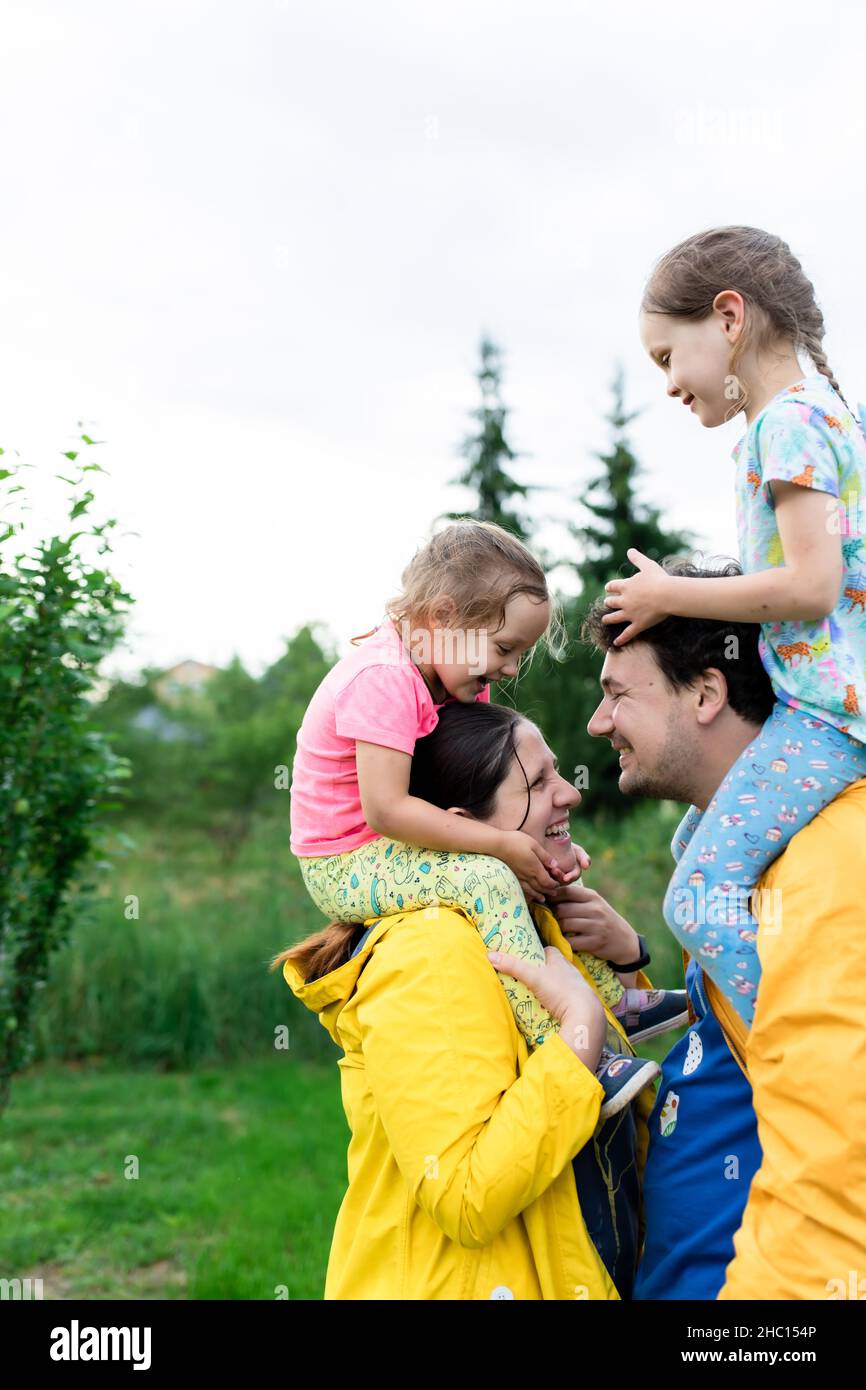 Una coppia sposata con bambini in impermeabile giallo nel cortile posteriore. Vista frontale. Foto Stock