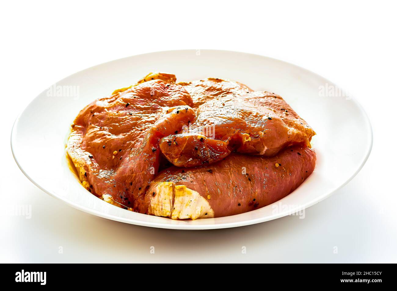Il maiale in marinata si trova su un piatto bianco su uno sfondo bianco isolato Foto Stock