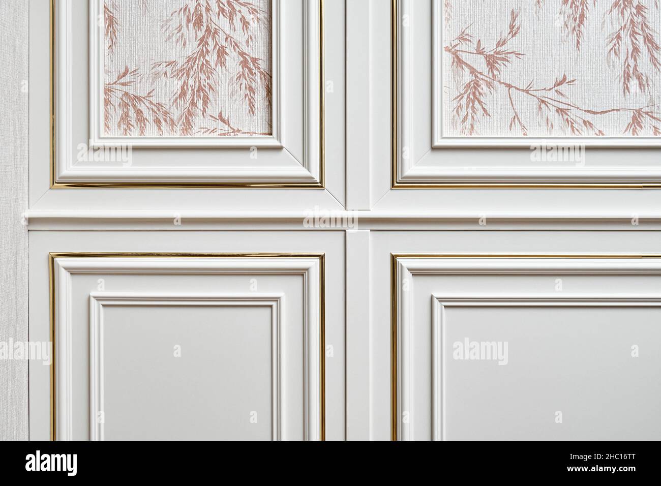 Pannello a parete bianco con stampaggio in oro in stile classico con carta da parati con motivo floreale in camera spaziosa e luminosa di primo piano cottage Foto Stock