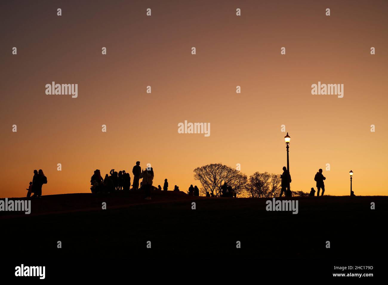 La gente si affacciava su un cielo al tramonto su Primrose Hill, un luogo popolare per vedere la città di Londra. Foto Stock
