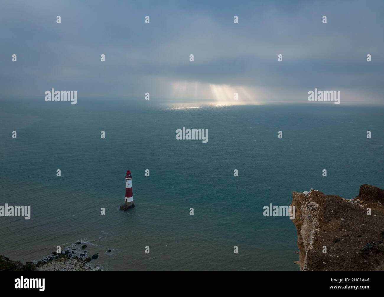 La luce del sole che si infrangono attraverso le folte nuvole di dicembre sopra il faro di Beachy Head sulla costa del Sussex orientale, nel sud-est dell'Inghilterra Foto Stock