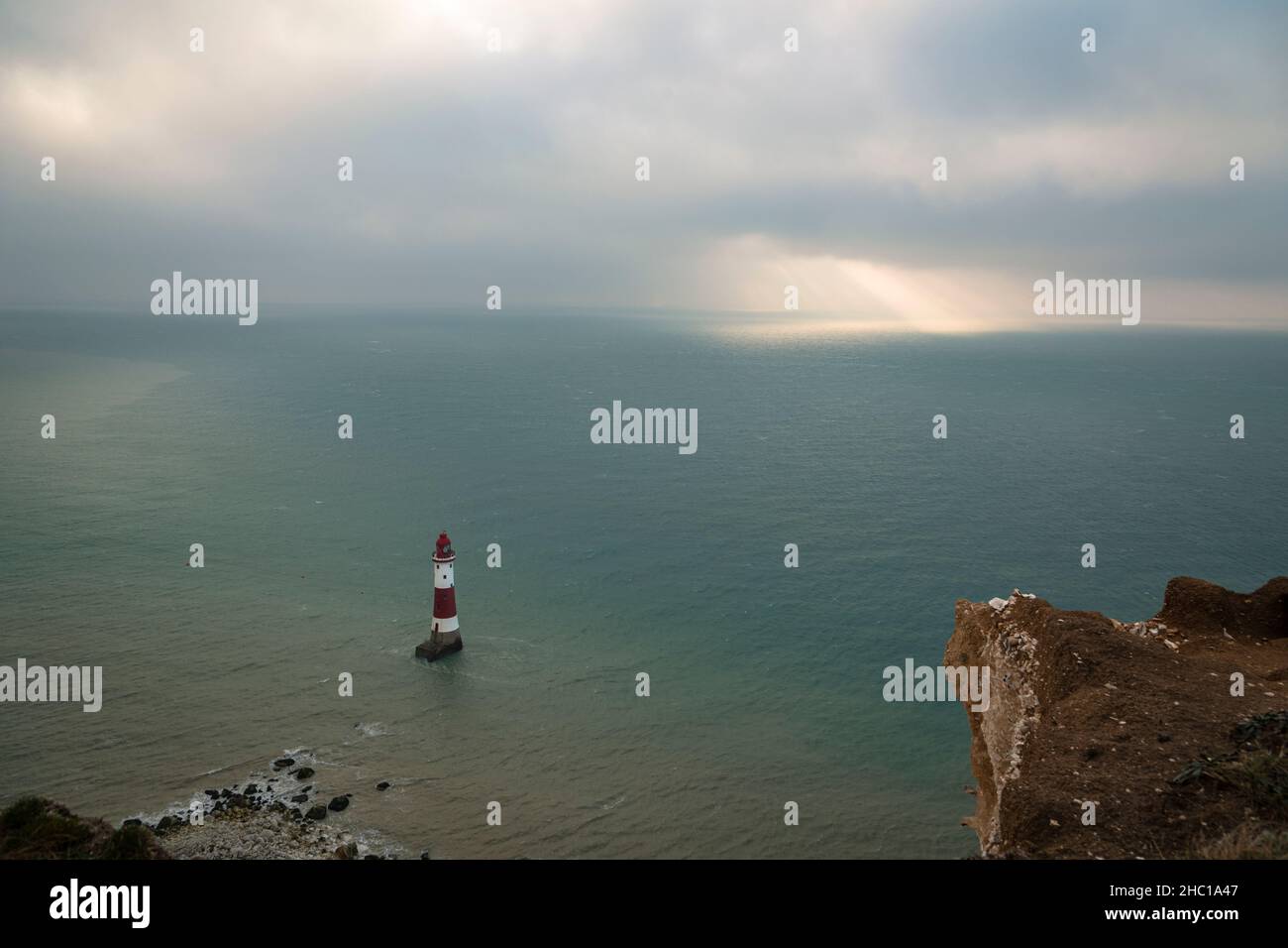 La luce del sole che si infrangono attraverso le folte nuvole di dicembre sopra il faro di Beachy Head sulla costa del Sussex orientale, nel sud-est dell'Inghilterra Foto Stock