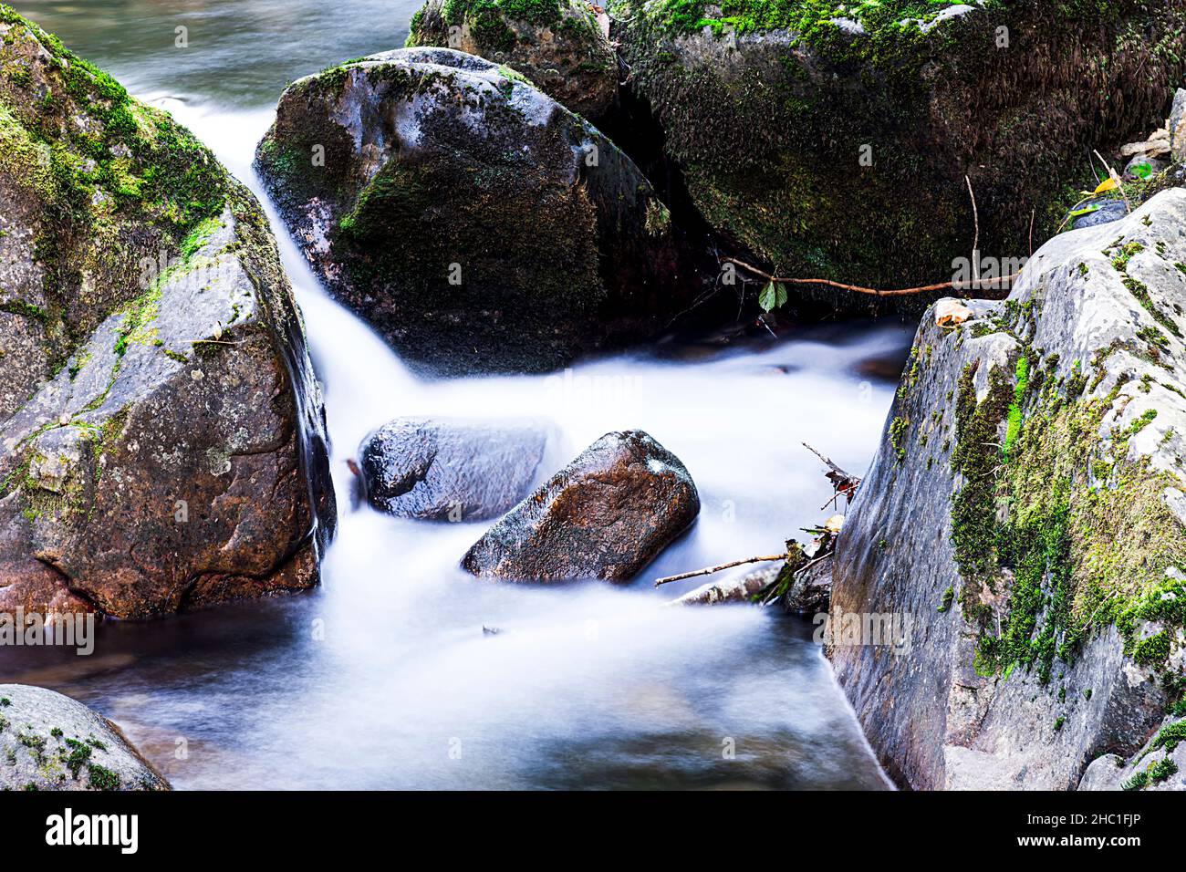 Primo piano di alcune rocce del fiume che corre lungo il percorso Alba nelle Asturie. La foto è stata scattata in formato orizzontale e con una lunga esposizione a. Foto Stock
