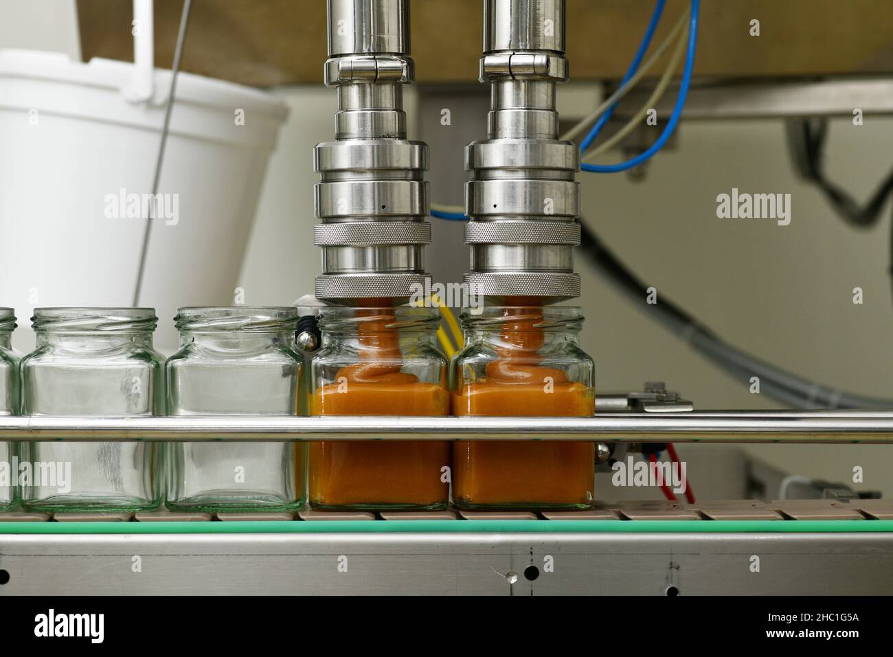 Vasetti di miele cremato che vengono riempiti in una linea di confezionamento in una fabbrica commerciale di miele Foto Stock