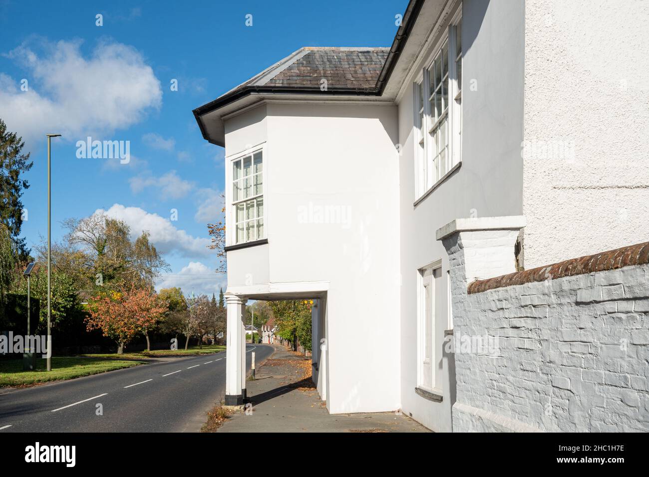 Insolita casa bianca con colonne che sostengono il primo piano sopra il marciapiede nel villaggio di Shalford, Surrey, Inghilterra, Regno Unito Foto Stock