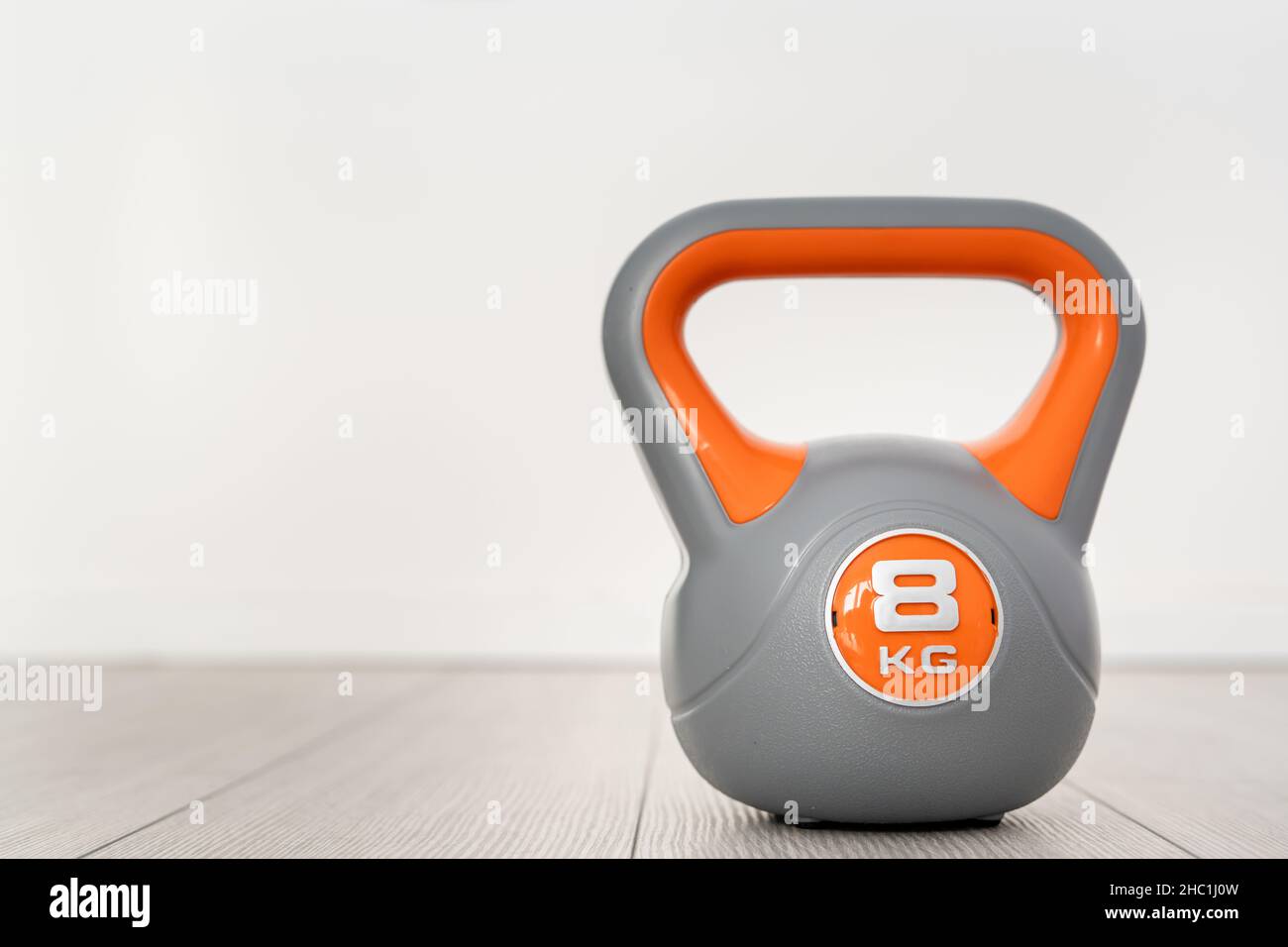 Un kettlebell in plastica da 8 kg di materiale didattico grigio e arancione sul pavimento Foto Stock