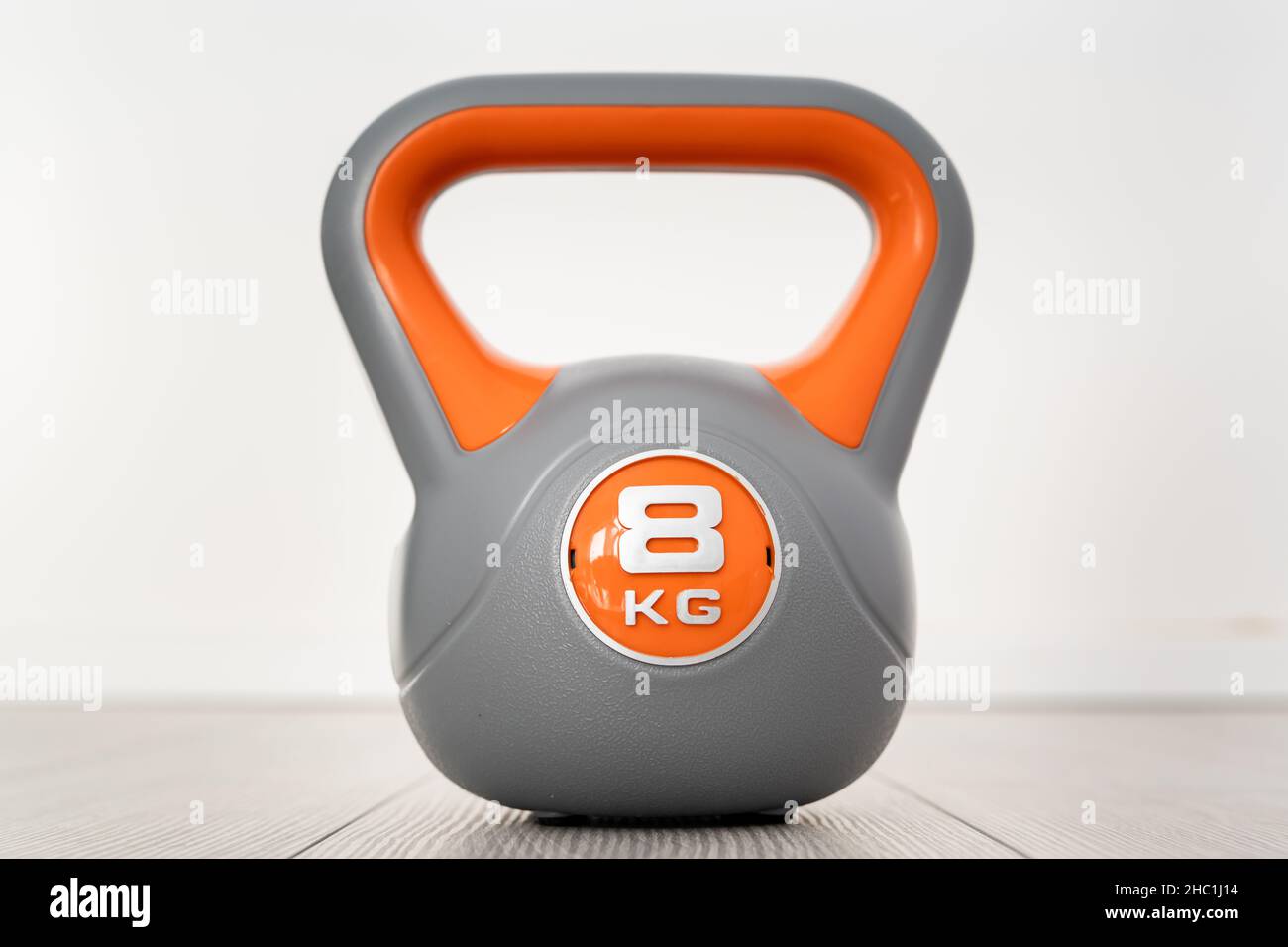 Un kettlebell in plastica da 8 kg di materiale didattico grigio e arancione sul pavimento Foto Stock Un kettlebell in plastica da 8 kg di materiale didattico grigio e arancione sul pavimento Foto Stock