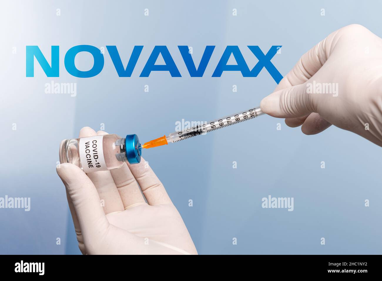 Torino, Italia - 18 dicembre 2021: infermiate le mani con guanti in lattice con siringa che preleva il vaccino dal flaconcino, sullo sfondo il logo Novavax Laboratory Foto Stock