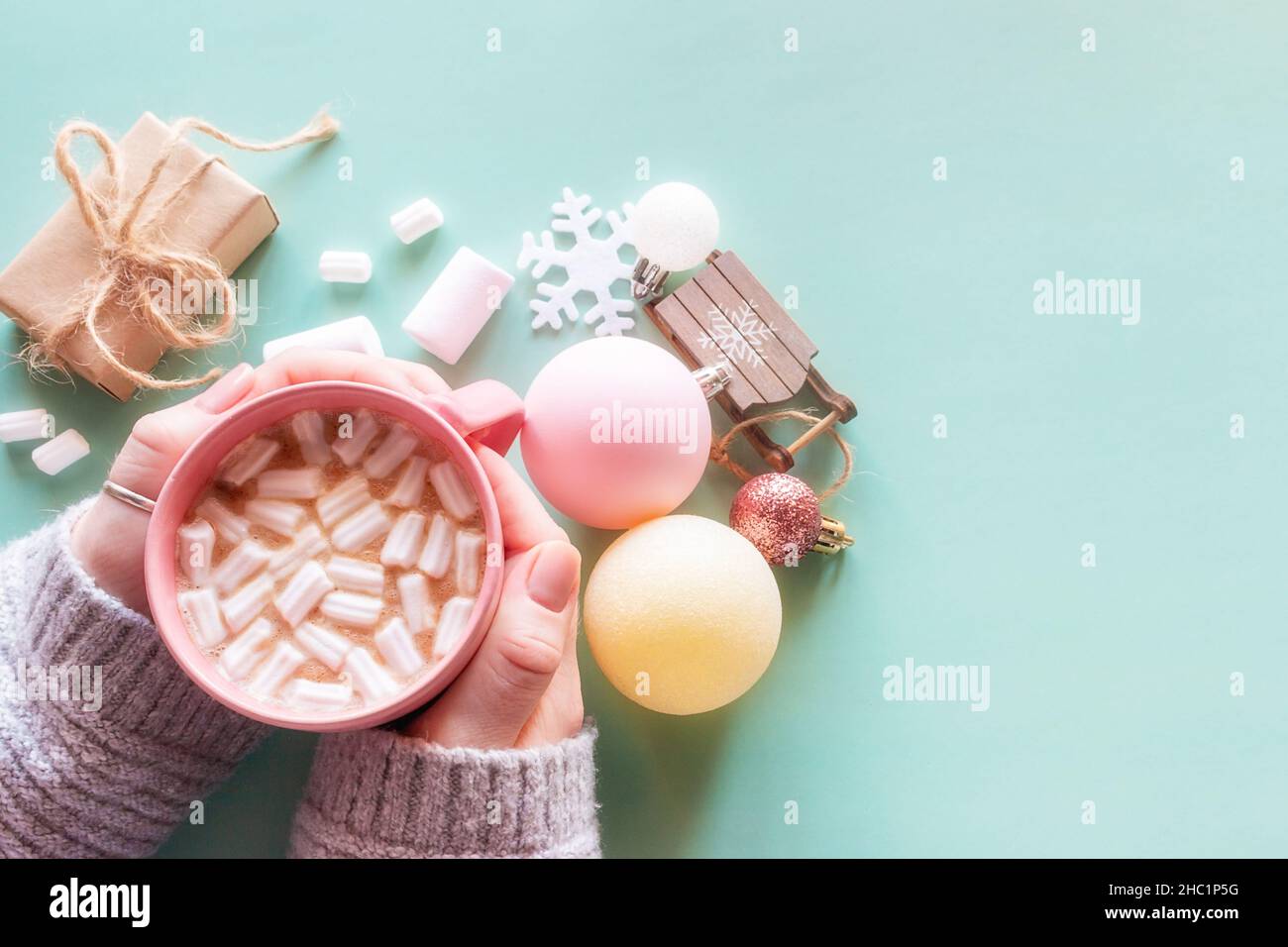 regali di nuovo anno, giocattoli, ragazza che tiene una tazza di caffè con marshmallows su uno sfondo verde con posto per il testo Foto Stock