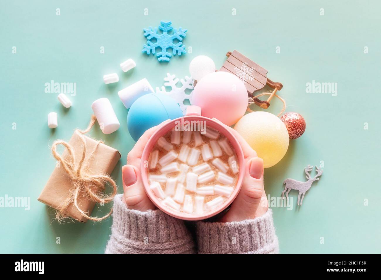 ragazza che tiene una tazza di caffè con marshmallows e decorazioni di nuovo anno su uno sfondo verde natale nuovo anno Foto Stock