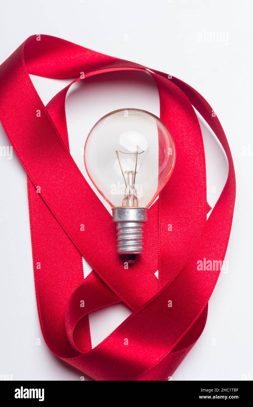 lampadine a incandescenza e nastro rosso su sfondo bianco Foto Stock