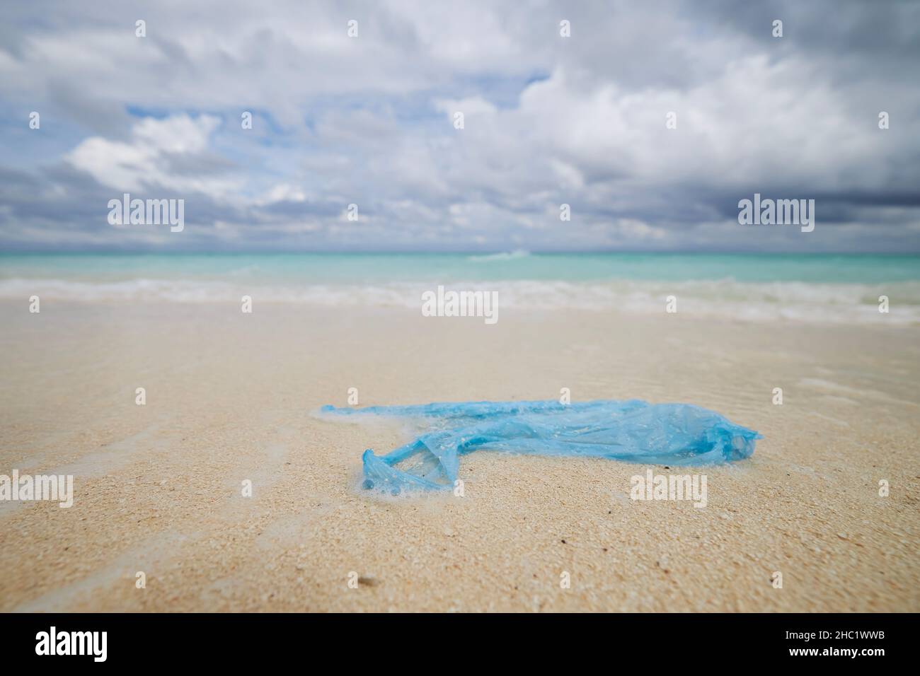 Borsa di plastica abbandonata sulla spiaggia di sabbia contro il mare. Temi dell'inquinamento degli oceani e questioni ambientali. Foto Stock