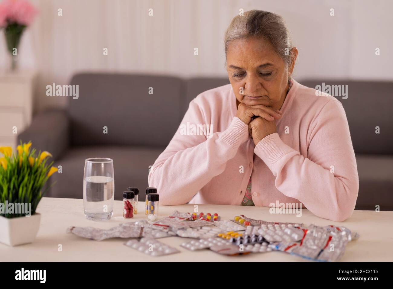 Donna anziana che sta per prendere la medicina tenuta sul tavolo centrale Foto Stock