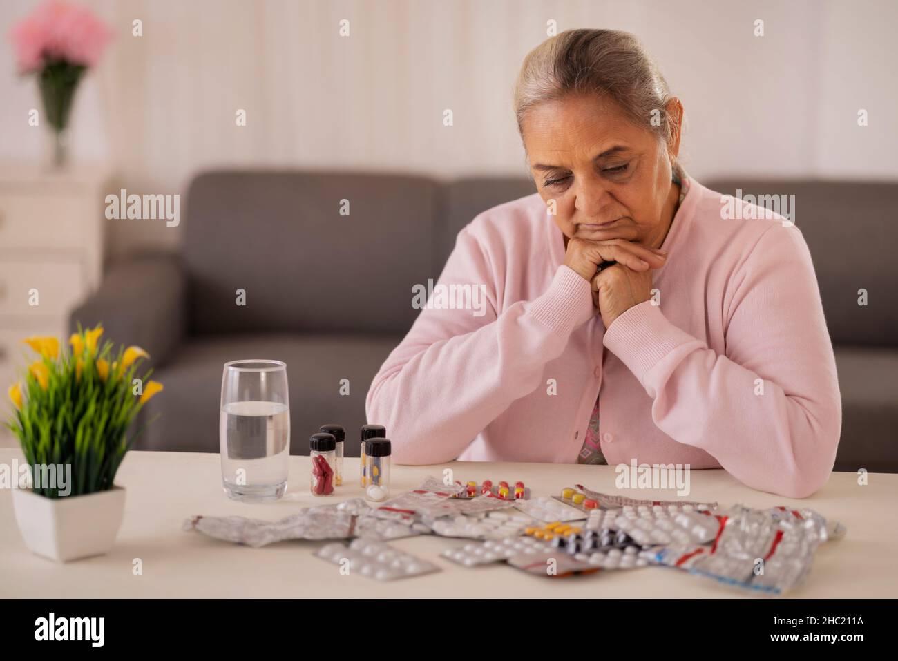 Donna anziana che sta per prendere la medicina tenuta sul tavolo centrale Foto Stock