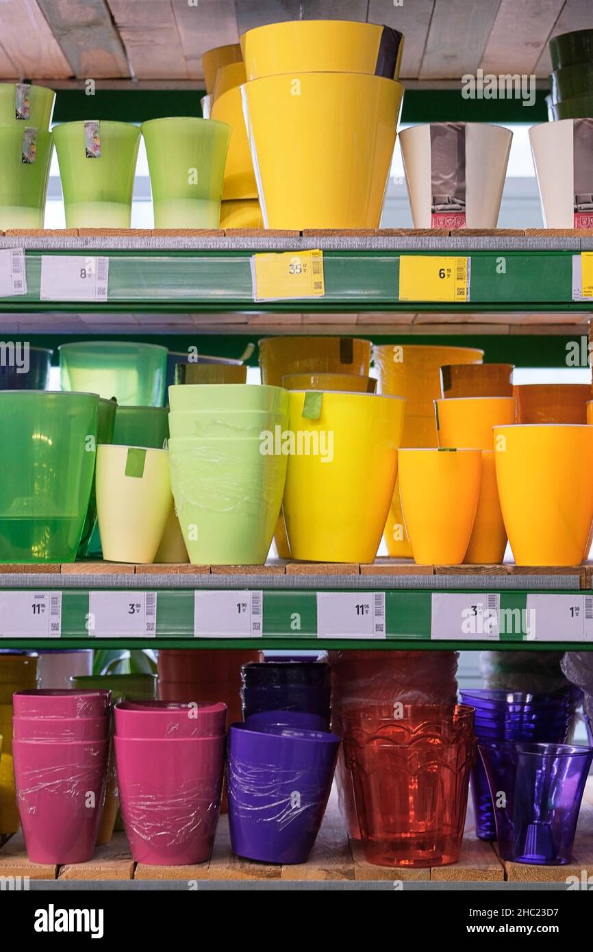 Pentole per le casalinghe sono vendute al deposito. File di pentole colorate diverse per piante interne su scaffali in un supermercato. Foto Stock