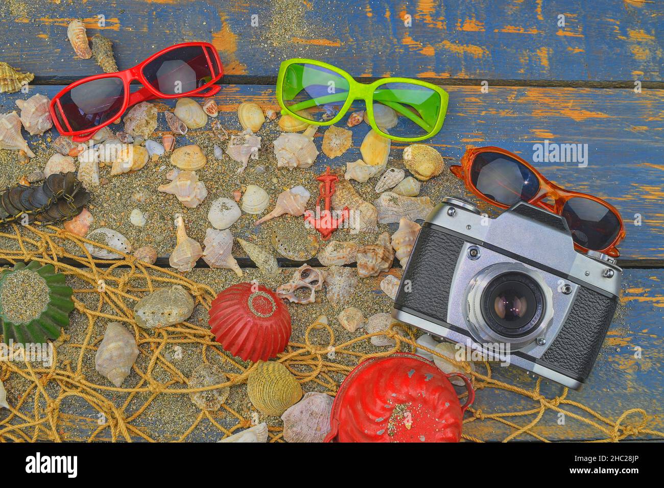 Conchiglie di mare su sfondo blu. Tempo di viaggio estivo. Sfondo vacanza mare con varie conchiglie, occhiali da sole e macchina fotografica d'epoca. Inserire il testo Foto Stock