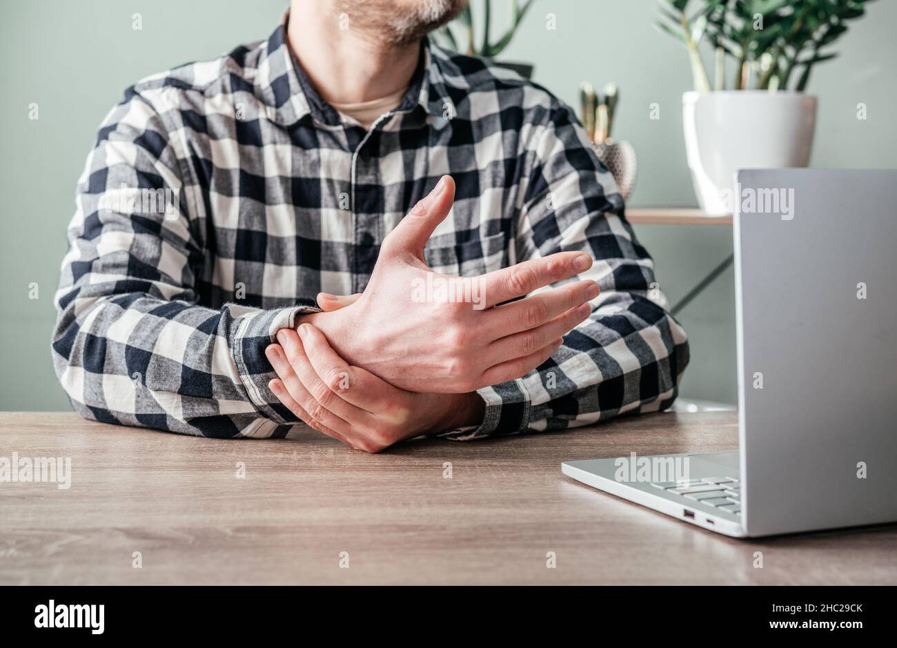 Un uomo che soffre di dolore articolare in mano e polso, artrite reumatoide e malattie professionali Foto Stock