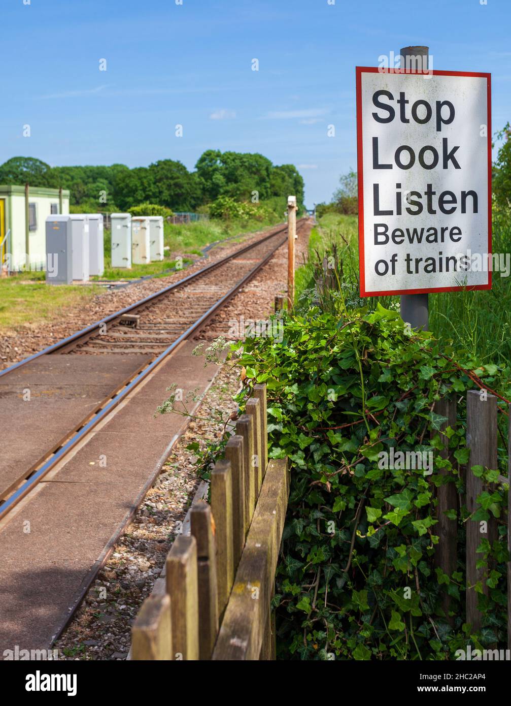 Vista di una fermata guarda attenzione al cartello dei treni accanto a un passaggio a livello su una linea ferroviaria a binario singolo nello Yorkshire Foto Stock