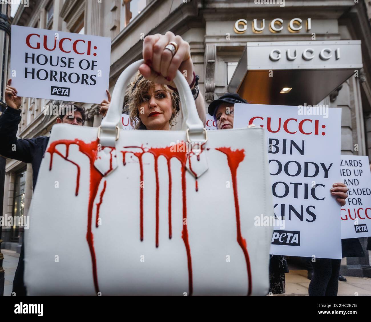 Gli attivisti tengono le borse spruzzate con sangue falso e cartelloni chiedendo che Gucci smette di utilizzare le pelli esotiche per i loro prodotti. Foto Stock