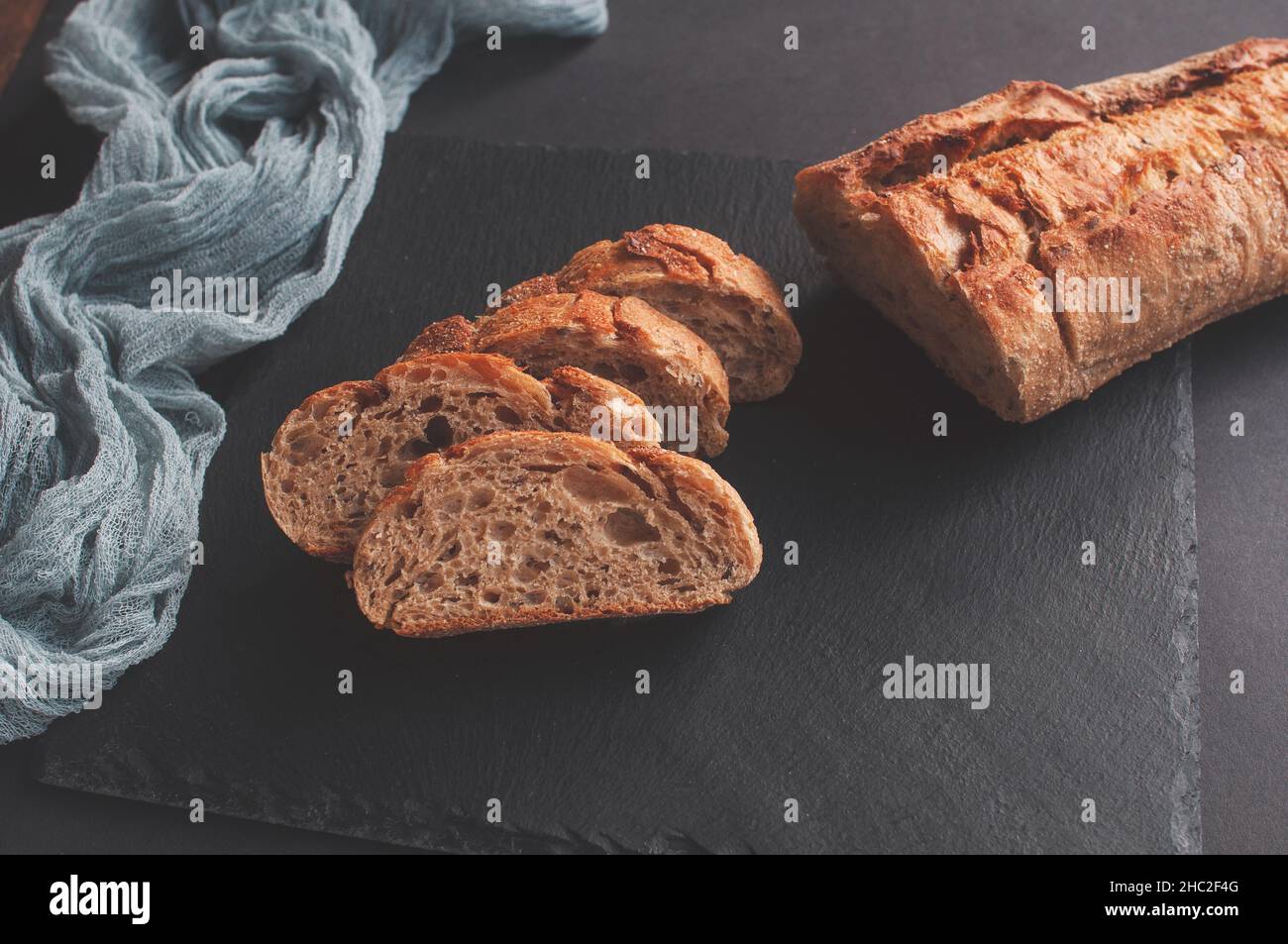 Baguette con selezione di pane francese fatta a mano con tovaglia di garza grigia su sfondo nero Foto Stock