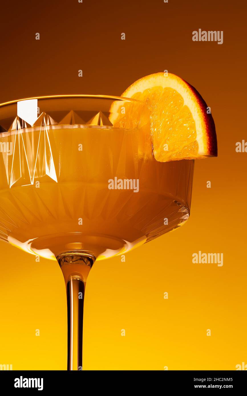 Primo piano bicchiere di cocktail mimosa senza alcool di frutta vegana. Rinfrescante mocktail di arancio festivo Foto Stock