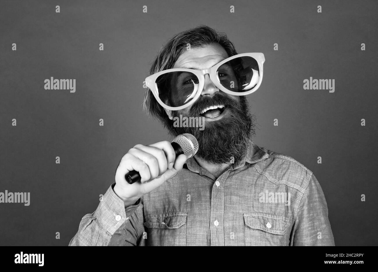 party goer. hipster uomo con barba indossare occhiali. concetto di musica. buona vacanza. buon divertimento a festa. cantante maschile cantare canzone nel microfono Foto Stock