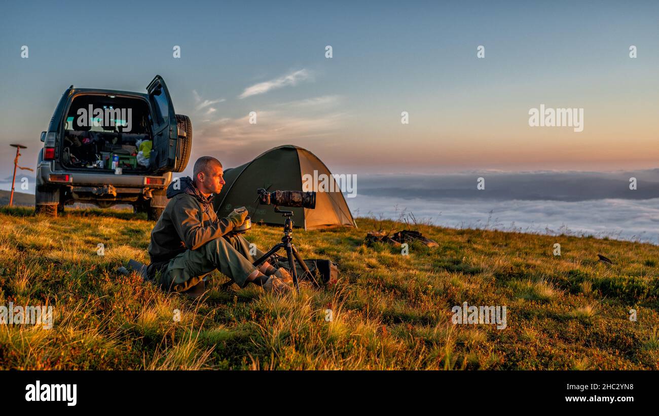 Un fotografo naturalistico che scatta foto dell'alba di montagna. Foto Stock