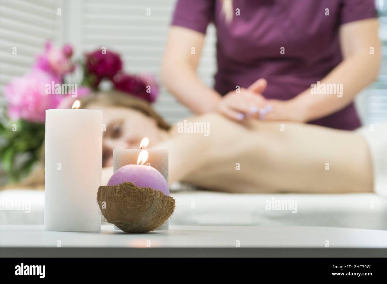 Bella giovane donna ottiene massaggio benessere sdraiato sul divano nel salone spa. Massaggio rilassante alla schiena Foto Stock