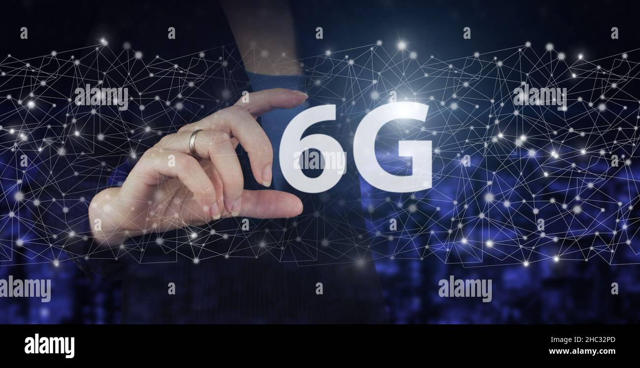 Il concetto di rete 6G, Internet mobile ad alta velocità, reti di nuova generazione. Mano Hold digitale ologramma 6G segno sulla città scuro sfondo sfocato. GL Foto Stock