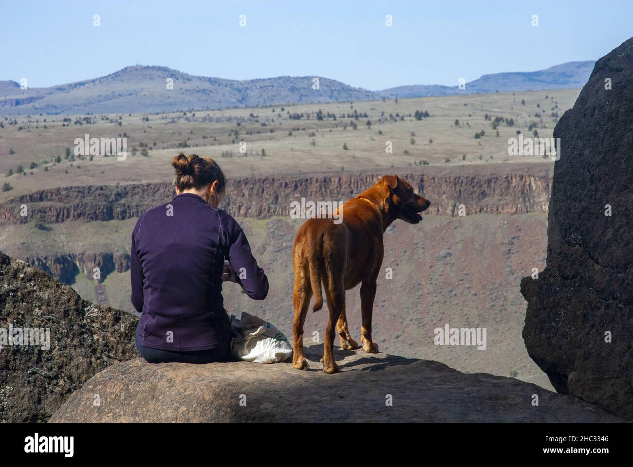 Single donna con cane si prepara a roccia in salita. Trout Creek, Oregon Foto Stock