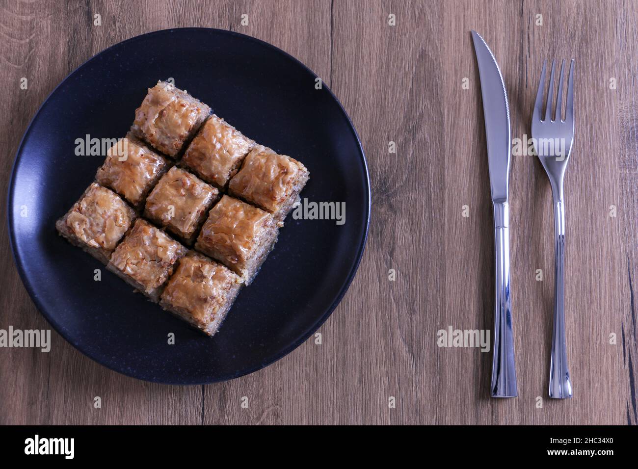 Baklava, dessert turco tradizionale chiamato Baklava in un piatto nero su sfondo di legno. Fuoco selettivo sul baklava centrale. Concetto di Ramadan Foto Stock