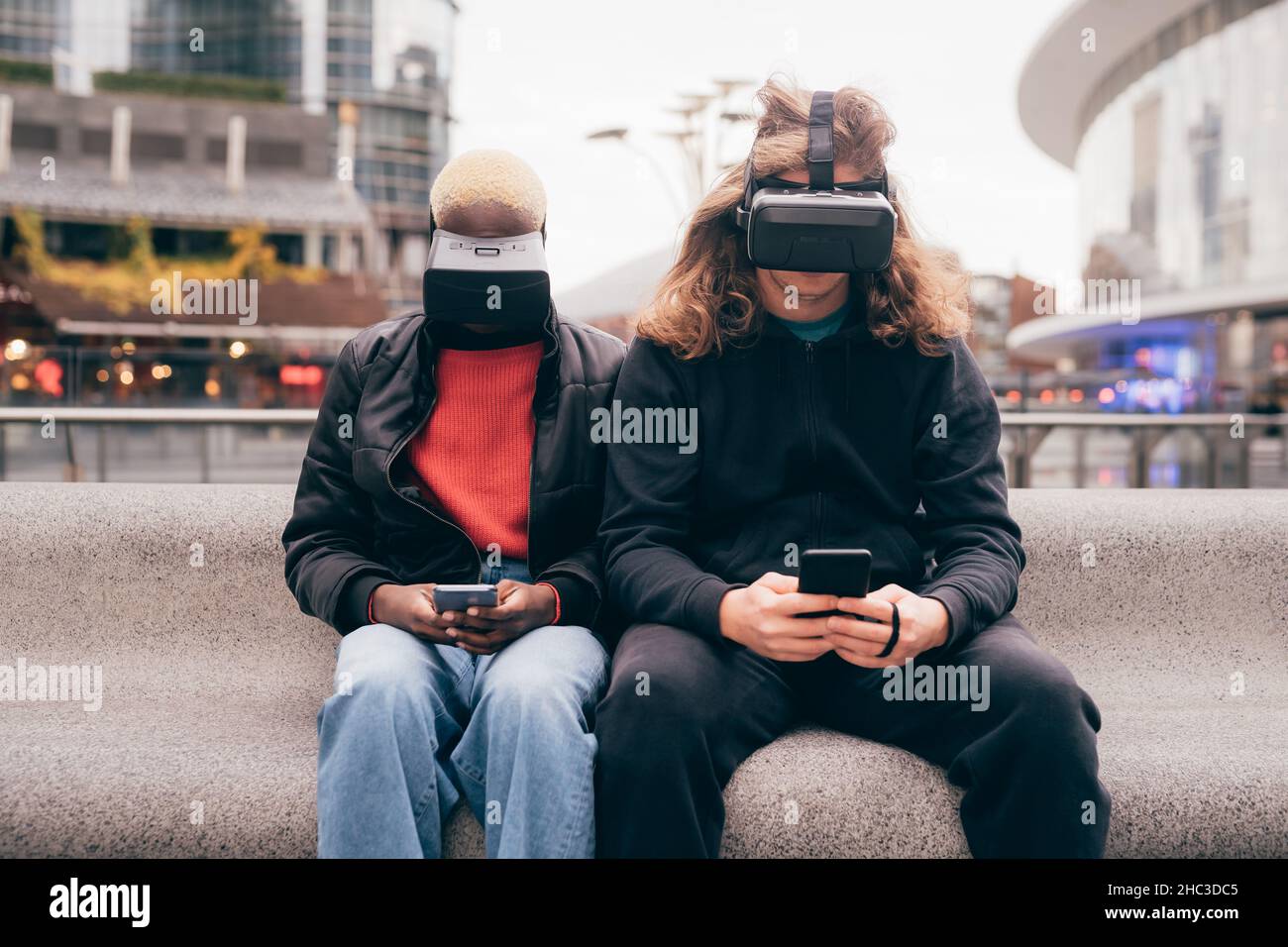 Italia, coppia con occhiali di protezione per la realtà virtuale e smartphone in città Foto Stock