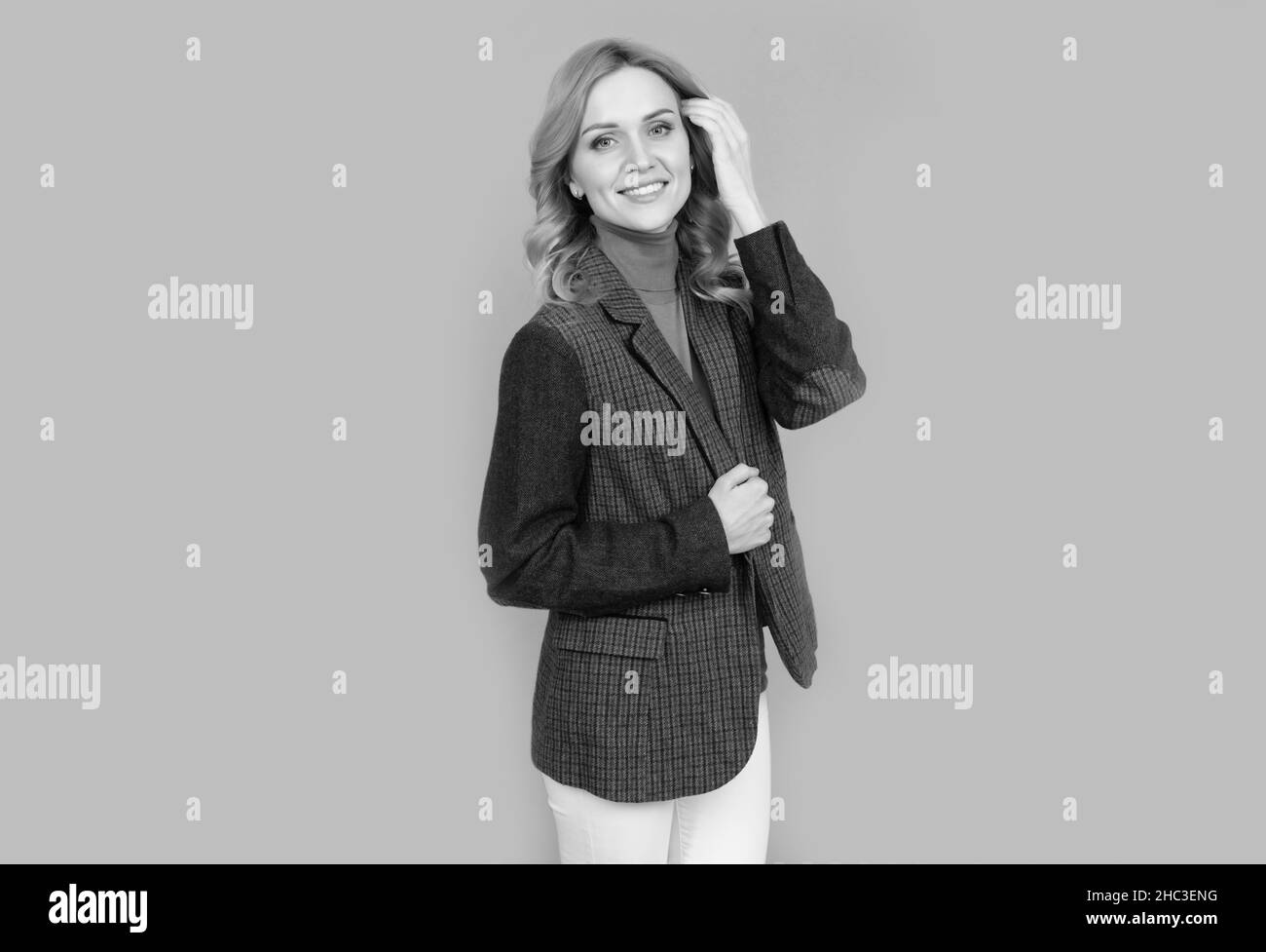 donna allegra in affari casual giacca britannica su sfondo grigio, bellezza Foto Stock