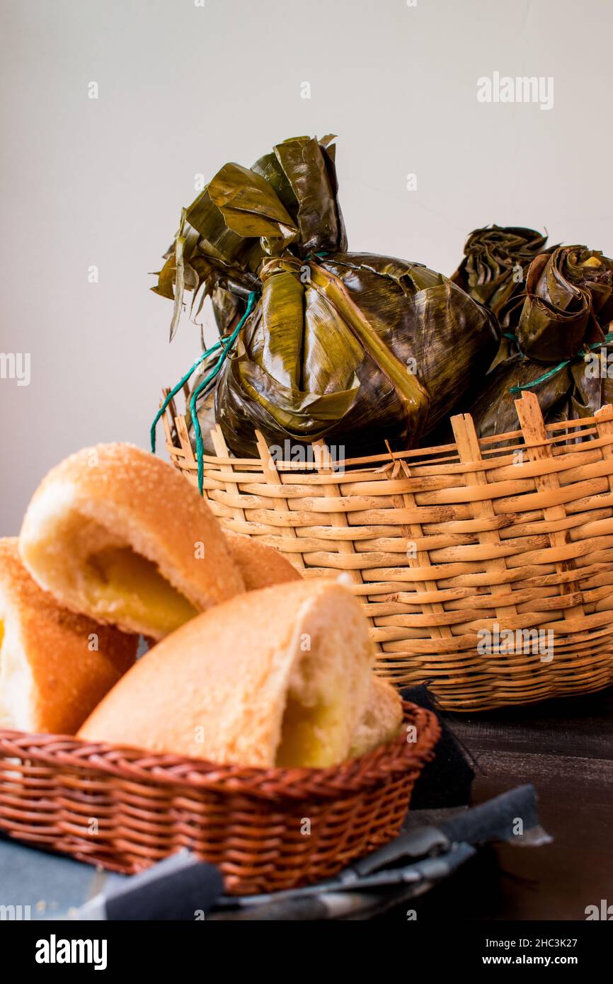 Tradizionale cibo colombiano noto come 'tamal' avvolto con foglie in un cestino su un tavolo nero Foto Stock