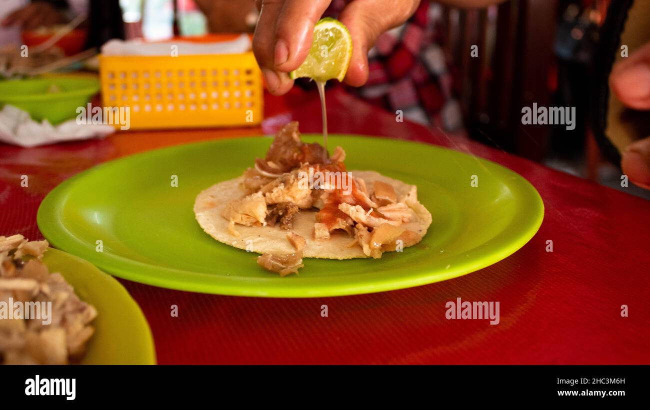 uomo messicano che mette il succo di lime sulle sue carnitas tradizionali tacos di Michocan. Foto di alta qualità Foto Stock