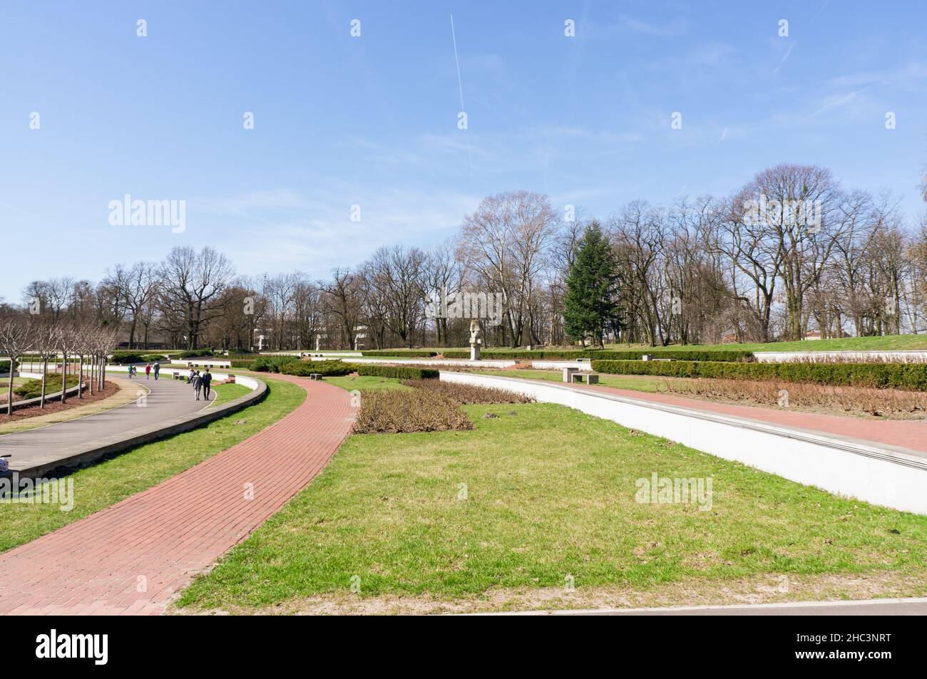 Poznan, Polonia - 7 aprile 2018: Sentiero e erba con alberi sullo sfondo del parco Cytadela in una calda giornata di primavera Foto Stock